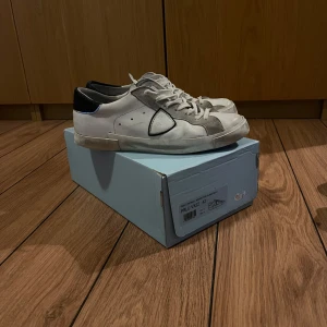 Philippe Model skor  - Snygga vita sneakers från Philippe Model med grå detaljer och svart häl. Skorna har en klassisk design med snörning och en diskret logga på sidan. Box och påse medföljer, mvh Teo😃vid frågor eller funderingar så är de bara att skriva 