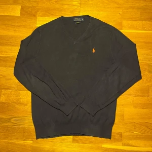 Ralph Lauren tröja - Säljer en stilren marinblå tröja från Ralph Lauren med v-ringning och det klassiska broderade logotypen på bröstet. Skick: 9/10. Både skönt,varmt och snyggt nu till vintern. 