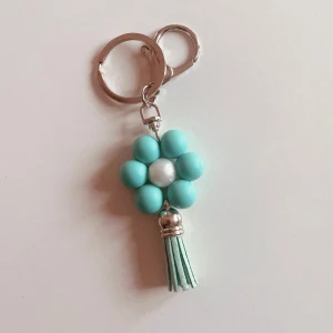 Nyckelring med silikon pärlor  - Charmig nyckelring med en turkos blomma gjord av pärlor och en dekorativ tofs. Perfekt som accessoar för att ge nycklarna en personlig touch.🌸