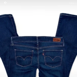 Mörkblå jeans från Levi's - Snygga mörkblå jeans från Levi's med klassisk femficksdesign och ikonisk bakficka med bågformad söm. Perfekta för en avslappnad stil. De har en knappgylf och är tillverkade i slitstarkt denim. Skulle säga att de är lågmidjade. Storlek 29 men sitter bra på mig som har 26/27🫶🏻Fråga bara om du undrar något
