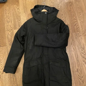 Svart parkajacka från Everest - Säljer en svart parkajacka från Everest. Jackan har en praktisk huva och långa ärmar. Perfekt för kyligare dagar med sin stilrena design och funktionella fickor. Passar bra för både stad och natur.