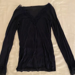 Mörk blå långärmad topp från Intimissimi - Elegant mörk blå långärmad topp från Intimissimi med spetsdetaljer vid halsringningen. Sällan använd och är i bra skick