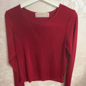 Röd långärmad topp från Jacqueline de Yong - Snygg röd långärmad topp från Jacqueline de Yong. Perfekt för både vardag och speciella tillfällen. Enkel design med rund halsringning.