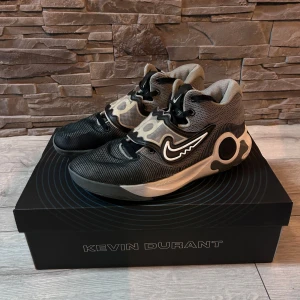 NIKE KD TREY IX  - Snygga Kevin Durant sneakers i svart och grått med coola detaljer och snörning. Perfekta för basket eller vardagsbruk. Skorna har en unik design med märkets logga på sidan och en bekväm passform.