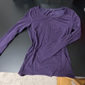 Lila långärmad topp - Säljer en stilren lila långärmad topp i mjukt material. Perfekt för lager-på-lager eller som den är. Enkelt och bekvämt plagg för vardagsbruk.