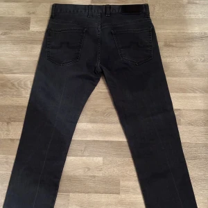 Svarta jeans från J.Lindeberg - Snygga svarta jeans från J.Lindeberg med en rak passform i storlek W31/L32 dom är dock mindre i både midja och längd så kontakta mig vid intresse och skriv vad för mått du behöver så löser jag det. 