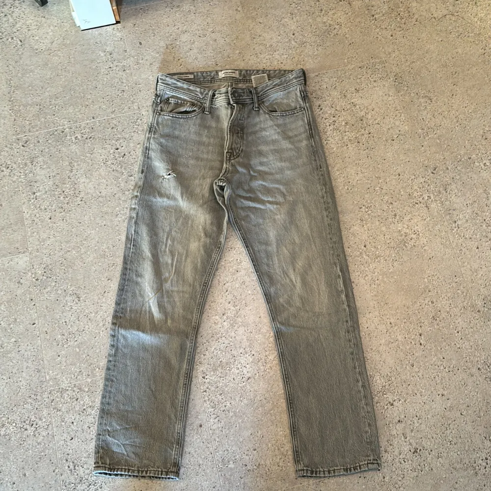 Säljer dessa gråa jack & jones Chris jeans som är knappt använda pga hål i höger ben. Men de går fortfarande att använda, pris kan snackas. Jeans & Byxor.