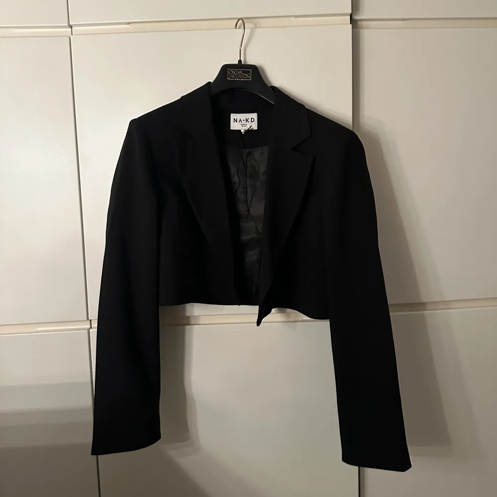 Croppad svart blazer från NA-KD, endast använd en gång (snörena som finns på modell bilderna har klippts bort), skriv för fler bilder. Kostymer.