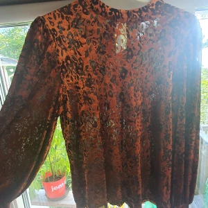 Leopardmönstrad blus från Stockh LM - Säljer en snygg leopardmönstrad blus från Stockh LM i storlek XS. Blusen är i en härlig brun färg med svarta och orangea detaljer. Den har långa ärmar och är perfekt för höst och vinter. Materialet känns lätt och luftigt, vilket gör den bekväm att bära både till vardags och fest.