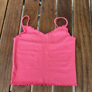 Rosa ärmlös topp med volangdetaljer - Säljer min tyvärr för liten söt rosa topp, lappen är dock bortklippt så vet inte exakt storleken men gissar XS-S💕Toppen är ganska croppad💕Det går inte att justera axelbanden💕Perfekt för sommarn eller som ett lager under en kofta💕den är i bra skick💕