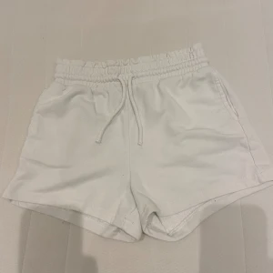 Vita shorts med dragsko - Säljer ett par vita shorts med dragsko i midjan. De är superbekväma och perfekta för sommaren. Shortsen har en elastisk midja och är gjorda av mjukt material. Perfekta för en avslappnad dag eller träning!