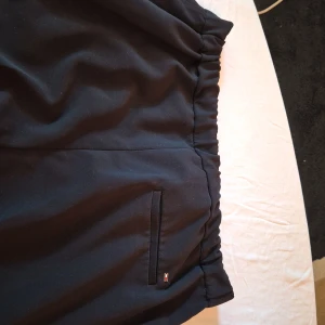 Svart kavaj från Tommy Hilfiger - Säljer en snygg svart kosty byxa från Tommy Hilfiger i storlek EUR 42 (US 10, UK 14). Kostym byxan  har en klassisk design med en liten logotypdetalj på bakfickan. Perfekt för både formella och semi-formella tillfällen. Den är i mycket bra skick och har en normal passform. Köp direkt eller ge prisförslag 💼