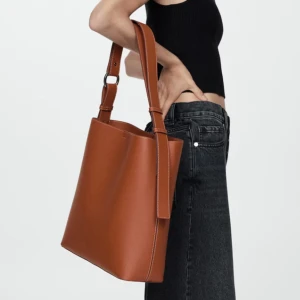 Mango väska - Säljer denna väskan då jag ångrade mig men hann ta bort prislappen. Den är alltså aldrig använd. Köpt på mango för 599kr och den heter ”Short handle shopper bag”. Den är väldigt fin i materialet och rymlig så funkar toppen som skolväska eller liknand