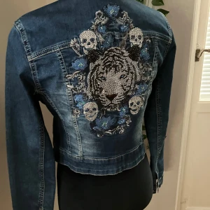 Jeansjacka med strass från She Wants - Helt ny super cool jeansjacka med glittriga strassar och brodyr på ryggen från She Wants, strl XS.