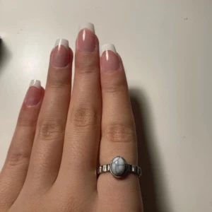 Silverring med vit sten - Säljer en snygg silverring med en vit sten i mitten. Ringen har en cool design med räfflad struktur runt om. Perfekt för att ge din outfit en extra touch! 💍✨ Den är köpt i Frankrike 🇫🇷 