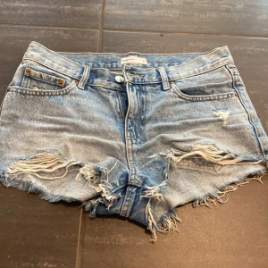Blå jeansshorts med slitningar - Säljer ett par snygga blå lågmidjade jeansshorts med slitningar. De är i storlek 34 som motsvarar xs och S och är ifrån Gina Tricot. Superbra skick!!💞💗