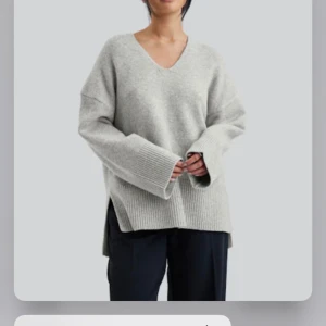Grå stickad tröja med v-ringning - Säljer en supermysig grå stickad tröja med v-ringning. Den har en oversized passform och långa ärmar med breda ribbstickade muddar. Perfekt för höst och vinter! 🧶