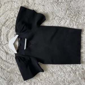 Svart topp - Svart v-ringad topp med fladdriga ärmar, stretchigt material, storlek xs från Vero moda. 