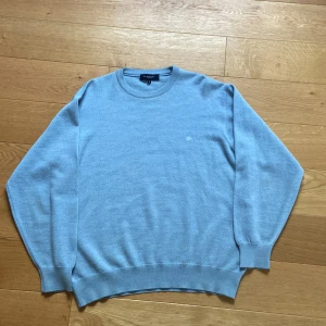 Burberry Merinotröja - Ljusblå tröja från märket Burberry i merinoull. Perfekt till vintern då den håller värmen bra. Skick 9,5/10, en liten fläck längst ner på armen men inget man märker av. Nypris 9000kr+, mitt pris 1800kr
