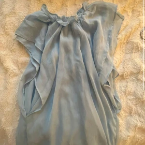 Ljusblå festtopp  - Säljer en superfin ljusblå festtopp från Zara. Den har en luftig och bekväm passform med korta ärmar och en rundad halsringning. 