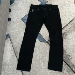 Svarta jeans från G-Star RAW - Säljer ett par snygga svarta jeans från G-Star RAW. De har en klassisk femficksdesign med knappar och dragkedja. Jeansen är i en stilren svart färg och har en slim passform. Storlek 33 , 34 ordinarie pris 2200 
