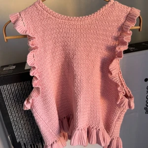 Rosa stickad topp från Zara - Säljer en superfin rosa stickad topp från Zara. Den har volangdetaljer längs sidorna och en ribbad kant längst ner. Perfekt för vår och sommar! 💖