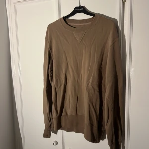 Beige tröja från Uniqlo - Säljer en snygg beige tröja från Uniqlo i storlek S. Den är gjord av en skön blandning av bomull och polyester, perfekt för både vardag och mysiga stunder. Tröjan har en klassisk design med långa ärmar och ribbade kanter vid hals, ärmslut och nederkant.