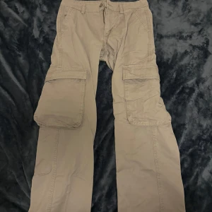 Gråa Cargopants - Gråa cargopants (midwaist) från Gina Tricot (köpte de 2022). Har inte använt de på ett bra tag, inget fel med byxorna (inga hål eller så i byxorna) Storlek: 34 (XS) Inga tecken på användning!!!