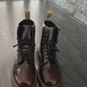 Bruna kängor från Dr. Martens - Säljer ett par snygga bruna kängor från Dr. Martens i storlek 42. De har en klassisk design med snörning och den ikoniska gula sömmen runt sulan. Perfekta för både höst och vinter, och de är i nyskick! 