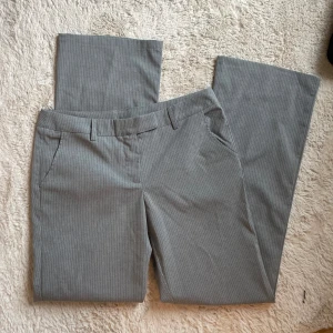 Grårandiga low waist kostymbyxor - Grårandiga kostymbyxor från asos. Med low waist och raka / utsvängda ben.  Storlek 38. Aldrig använda! 