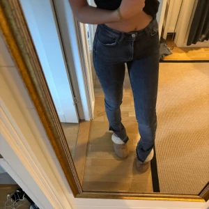 Svarta jeans - Säljer ett par grå/svarta jeans i slim fit. De är högmidjade och har en klassisk femficksdesign med knappar och dragkedja framtill. Perfekta för både vardag och fest! 