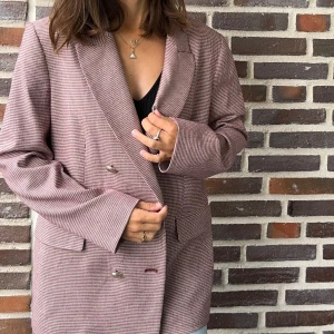 Rutig kavaj från Pennyblack - Säljer en superfin kavaj från Pennyblack med pied-de-poule-tryck. Den har en klassisk dubbelknäppt design med snygga metallknappar. Färgen är en blandning av vinrött och vitt vilket ger ett stilrent och tidlöst intryck. Perfekt för både vardag, kontor och kväll! Tillverkad av viskos och ull. Storlek: 40 FR / UK 12