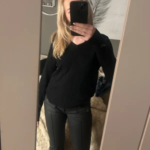 Svart v-ringad tröja - Säljer en stilren svart tröja med v-ringning. Tröjan har långa ärmar och en normal passform, perfekt för både vardag och mer uppklädda tillfällen.