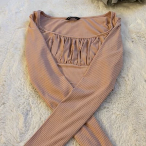 Rosa ribbad topp från Shein - Säljer en rosa ribbad topp från Shein med långärmad design och rynkade detaljer vid bysten. Perfekt för en stilren look.