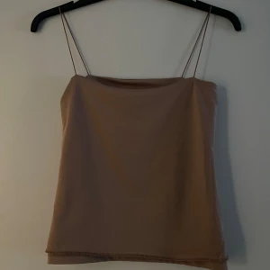 Beige axelbandslös tubtopp - Snygg beige tubtopp med tunna axelband. Perfekt för sommardagar eller som ett lager under en jacka. Enkel och stilren design som passar till det mesta.