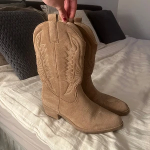  Cowboy boots - Snygga beiga cowboy boots med broderade detaljer. De har en spetsig tå och en låg klack. Endast använda vid ett tillfälle, de är storlek 40 men skulle säga att de även passar 39!