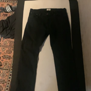Svarta jeans från Grant - Säljer ett par svarta jeans från Grant i regular fit. Klassisk design med fem fickor och en snygg läderpatch baktill. Perfekta för en stilren look.