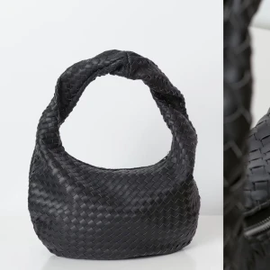 Svart flätad axelväska - Snygg svart axelväska med flätat mönster. Använd men fortsatt fint skick! Skriv för fler egna bilder. Nypris 499kr