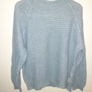 Ljusblå stickad tröja från 157 - Mysig ljusblå stickad tröja från 157. Perfekt för kyliga dagar med sin bekväma passform och långa ärmar. Den har en ribbad krage och ett fint stickat mönster som ger en stilren look.