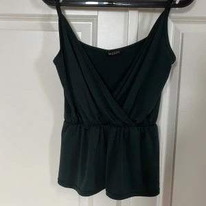 Mörkgrönt omlottlinne från Missay - Snyggt mörkgrönt omlottlinne från Missay med smala axelband och elastisk midja som tyvärr inte kommer till användning 🌟det står ingen storlek men skulle gissa på att den är M/L