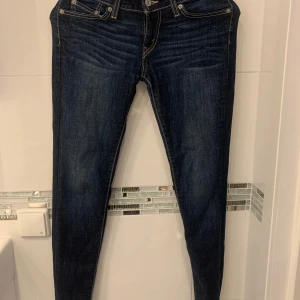 Mörkblå skinny jeans från Levi's - Snygga mörkblå skinny jeans från Levi's med klassisk femficksdesign och knappgylf. Perfekta för en stilren look. Low wist