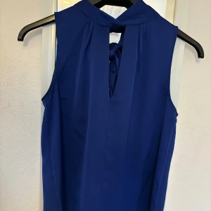 Blå ärmlös blus från Mango - Snygg blå ärmlös blus från Mango med rosett i nacken🎀 Den är lite mer mörkblå i verkligheten. Bara använd en gång!🫶🏼Storlek xs men passar mig som oftast har s💝