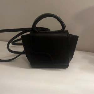 Svart axelväska från ATP Atelier - Snygg och kompakt svart axelväska från ATP Atelier i skinn. Väskan är använd som man kan se på andra bilden då det är några små repor, annars ingen större skada. Väskan är i micromodell så den funkar mer som att styla upp en outfit lite extra. ☺️