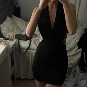 Svart kortklänning med djup urringning öppen rygg🥰 - Elegant svart kortklänning med djup v-ringad urringning. Klänningen är ärmlös och har en tight passform som framhäver figuren. Perfekt för en utekväll eller fest. Materialet är dock  tunnt 💕❤️