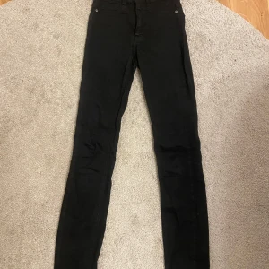 Svarta jeans från Perfect Jeans - Snygga svarta jeans från Perfect Jeans i modellen Molly. De är tighta och har en klassisk femficksdesign med knapp och dragkedja framtill. Perfekta för en stilren look.