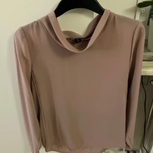 Rosa långärmad tröja - Säljer en stilren puderrosa  långärmad tröja med en elegant krage. Perfekt för både vardag och speciella tillfällen. Tröjan har en mjuk och bekväm passform.