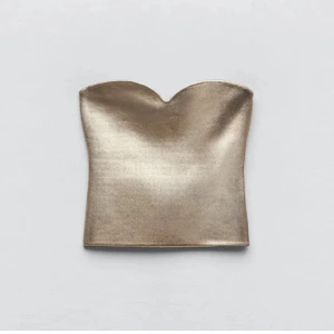 Guldig tubtopp - Snygg guldig tubtopp med en glansig finish. Perfekt för en kväll ute eller en festlig tillställning. Toppen har en stilren design utan axelband och en figurnära passform. 