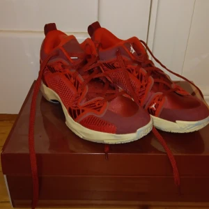 Röda jordans basket skor - Snygga röda Jordans med vit sula och ikonisk Jumpman-logga. Skorna har ett sportigt utseende med snörning och är perfekta för basketentusiaster. De har andväbts lite därflr är det färg under från sporthallar men går kanske att tvätta bort.