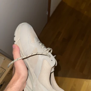 Beige sneakers från Axel Arigato - Snygga beige sneakers från Axel Arigato med en stilren design. Skorna har snörning och en robust sula för extra komfort. Perfekta för en avslappnad stil. Helt nya storlek 42,5. Ingen låda bara dust bag 