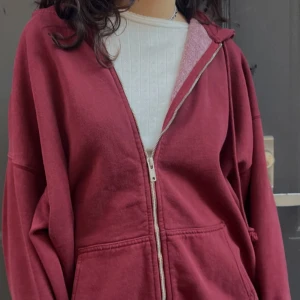 Brandy Melville zip-up hoodie - En vinröd zip up hoodie från Brandy Melville. Den är oversized så den passar dem flesta. Plagget är i nyskick och har knappt varit använt. Original priset på deras hemsida är ca 500kr